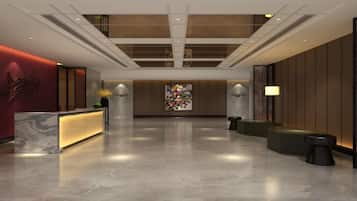 A modern hotel lobby with a reception desk, seating area, and a large open space.