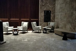 A modern lounge area with seating arrangements and a marble floor. - Bai Hua Ting International Hotel (Jinan)