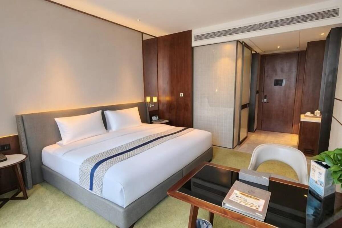 A hotel room with a bed, bedside table, chair, and a small desk with a chair.