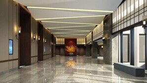 Un hall amplio y moderno con piso de mármol pulido, iluminación empotrada y un elemento decorativo central.