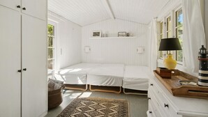 A white room with a bed, a lamp, and a small table with a lighthouse decoration.