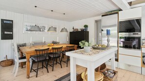 A dining area with a wooden table, black chairs, and pendant lights.
