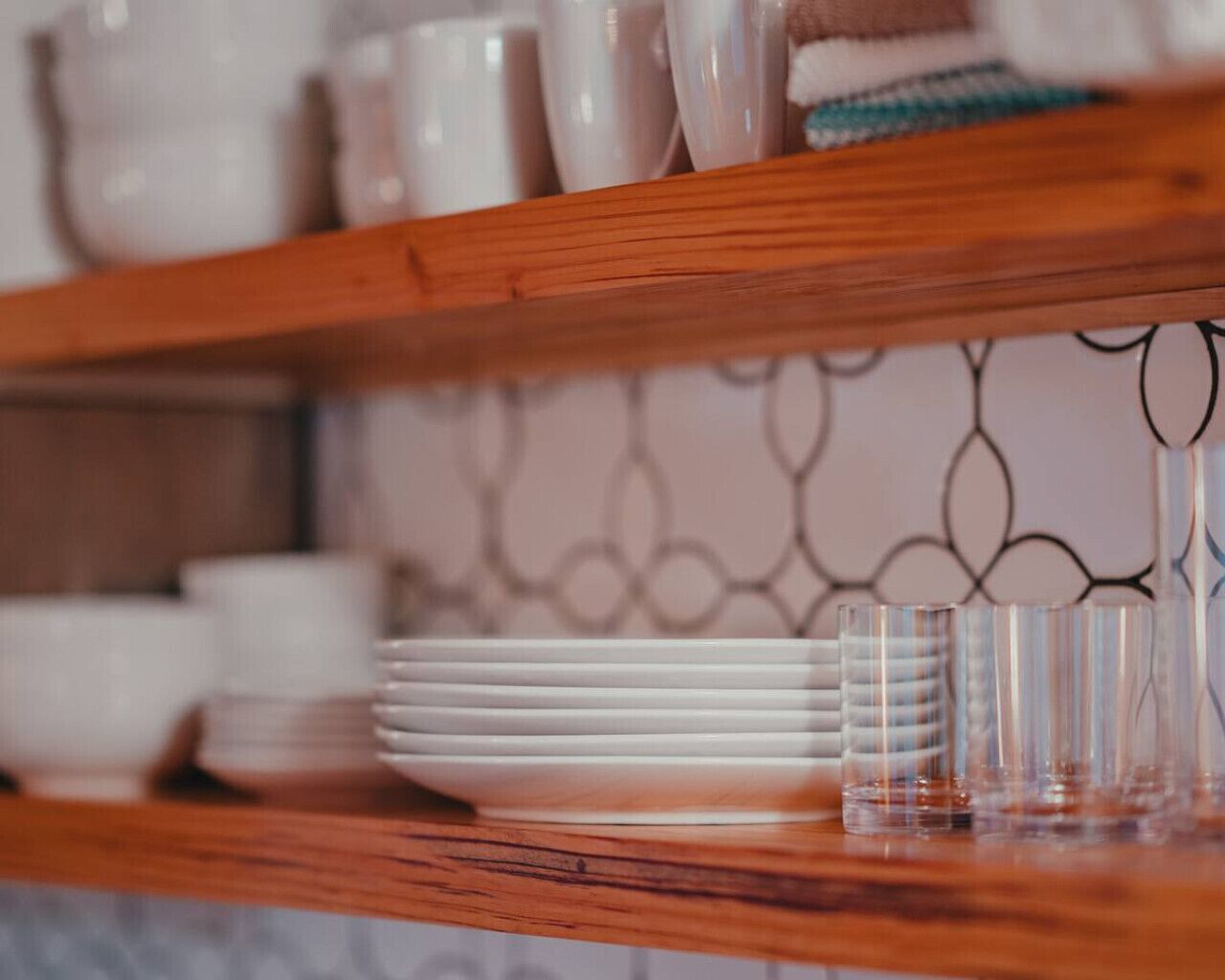 A kitchen counter with stacked white plates and clear glasses.