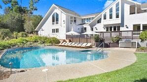 Une maison à deux étages avec une piscine, une terrasse dotée de chaises longues et une cour clôturée.