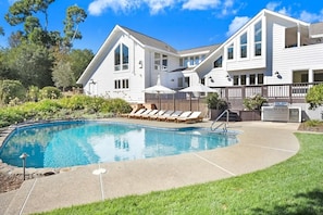 Une maison à deux étages avec une piscine, une terrasse dotée de chaises longues et une cour clôturée.