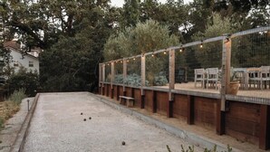 Un espace extérieur doté d’un sol en gravier, de bancs en bois et d’un coin salon couvert agrémenté de guirlandes lumineuses.