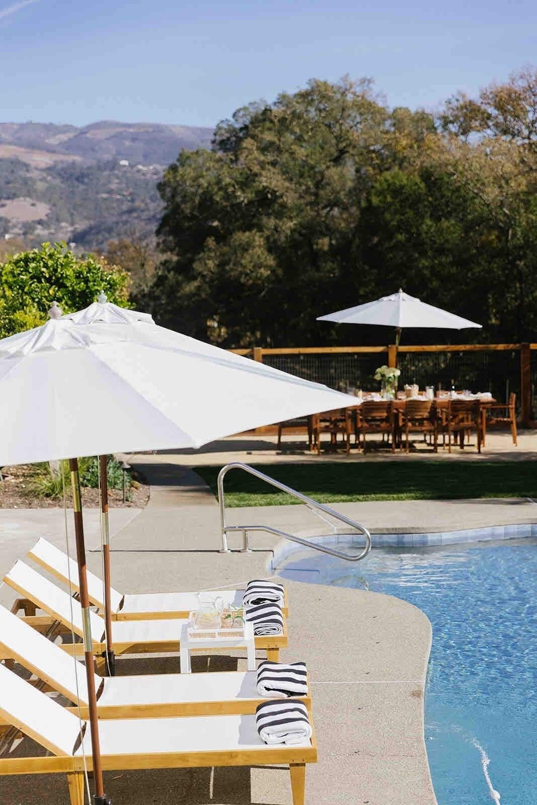Un espace aménagé au bord de la piscine, avec des chaises longues, une piscine et une vue sur les collines.