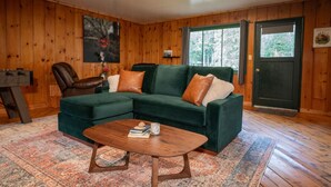 Ein gemütliches Wohnzimmer mit einem grünen Modulsessel, einem Ledersessel und einem Couchtisch aus Holz.