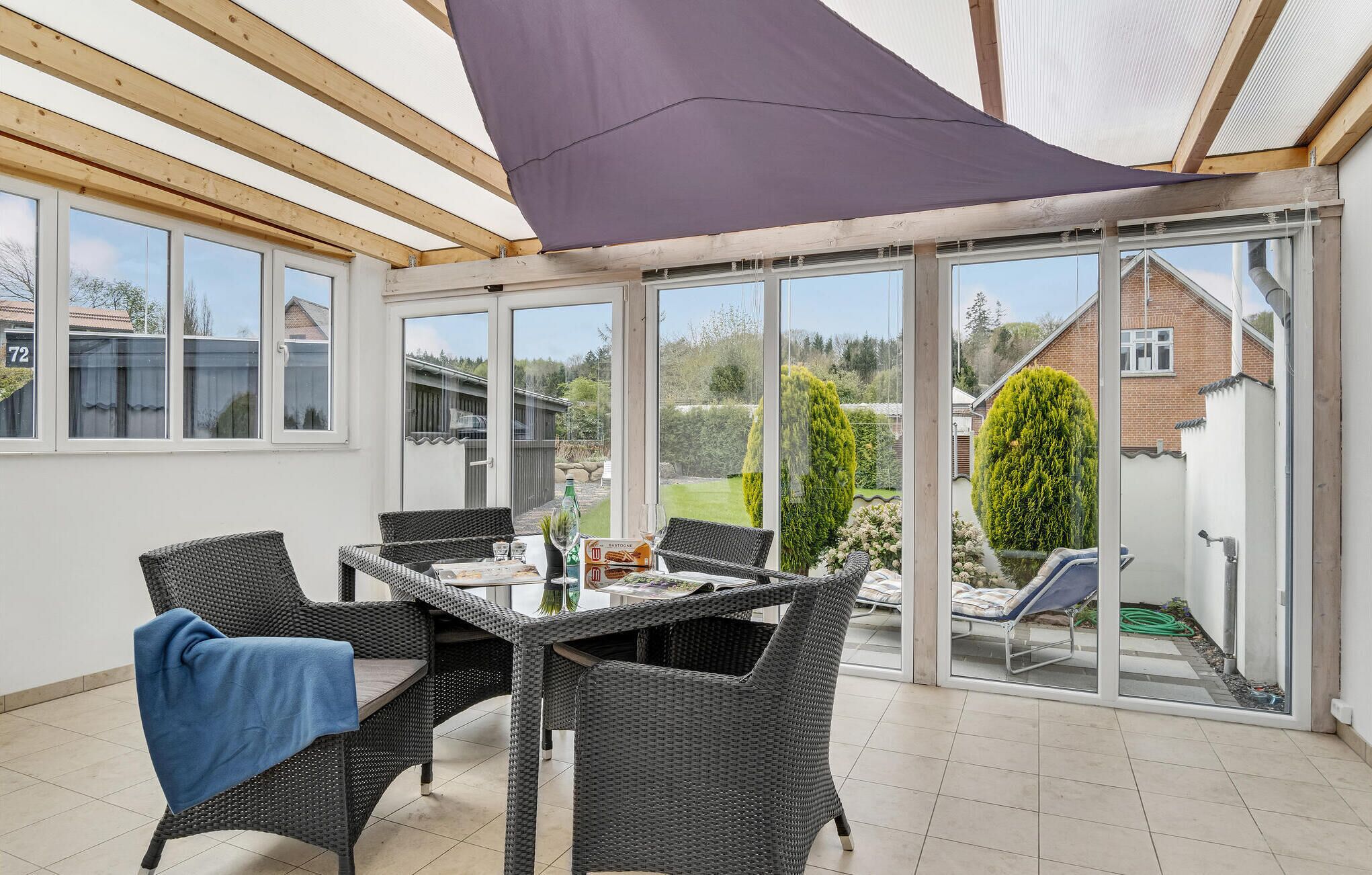 En overdækket terrasse med fletningsmøbler, et bord og et blåt håndklæde.