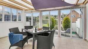 A covered patio with wicker furniture, a table, and a blue towel. - 4 bedroom amazing home in Mariager (Mariager)