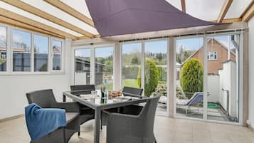 En overdækket terrasse med fletningsmøbler, et bord og et blåt håndklæde.