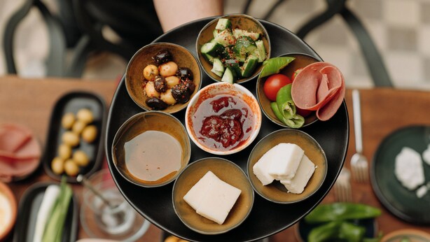 A table with various food items including olives, cheese, and vegetables. - Nill's Stone House Otel (Cesme)