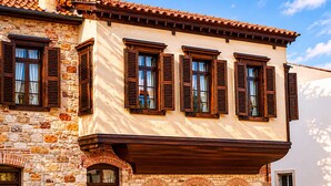 A building with stone walls, wooden shutters, and a tiled roof. - Nill's Stone House Otel (Cesme)