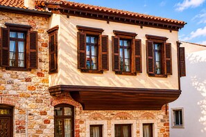 A building with stone walls, wooden shutters, and a tiled roof. - Nill's Stone House Otel (Cesme)