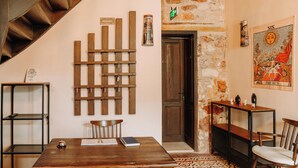 A room with a wooden table, chairs, a bookshelf, a staircase, and a door. - Nill's Stone House Otel (Cesme)