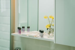 A bathroom vanity with toiletries and a vase of yellow flowers. - Nill's Stone House Otel (Cesme)