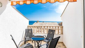 Ein Balkon mit Meerblick, einem Tisch und Stühlen sowie einem Geländer.