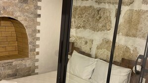 A room with a stone wall, a wooden bench, and a bed with white bedding. - Lutfiye Sigacik (Seferihisar)