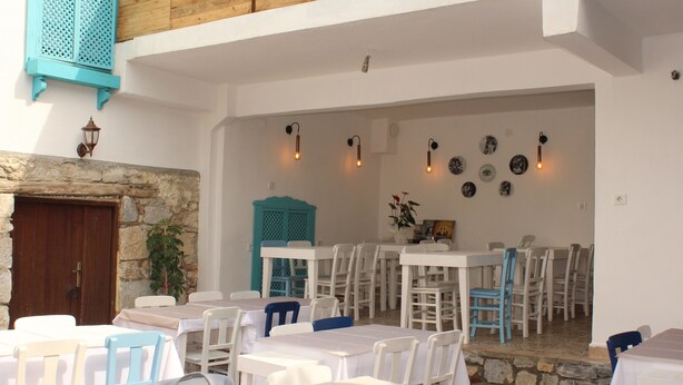 A restaurant with white tables and chairs, a stone wall, and a wooden ceiling. - Lutfiye Sigacik (Seferihisar)