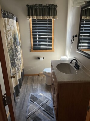 Un baño con inodoro, lavamanos y ventana con persianas.