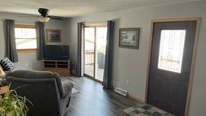 A living room with a sofa, television, and a sliding glass door leading to a deck. - Up North, Outdoor Enthusiast’s Paradise! (Birchwood)