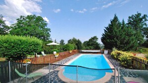 A rectangular swimming pool with a stone deck, surrounded by a wooden fence and a metal safety barrier. - Mobile home in Xaintrie (SAINT-GENIEZ-Ô-MERLE)