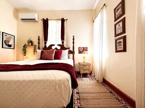 Una habitación de hotel con una cama grande, una mesita de noche con lámpara y una alfombra pequeña.