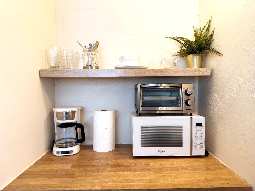A kitchen with a coffee maker, a toaster oven, and a microwave on a wooden countertop.