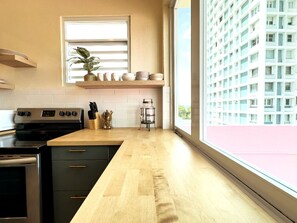 Una cocina moderna con encimera de madera, estufa integrada y ventana con vistas a un edificio.