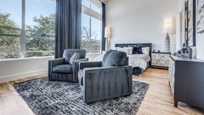 A modern bedroom with a large window, a ceiling fan, a bed, a desk, and two armchairs. - 2912 Raleigh (Dallas)