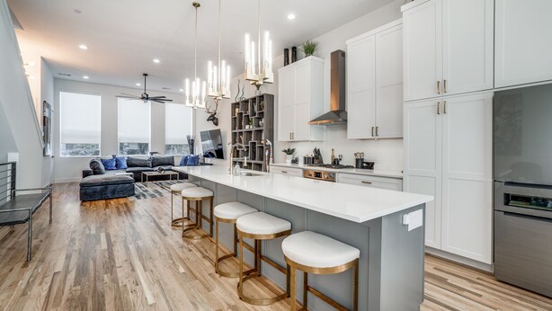 A modern kitchen with a large island, bar stools, and white cabinetry. - 2912 Raleigh (Dallas)