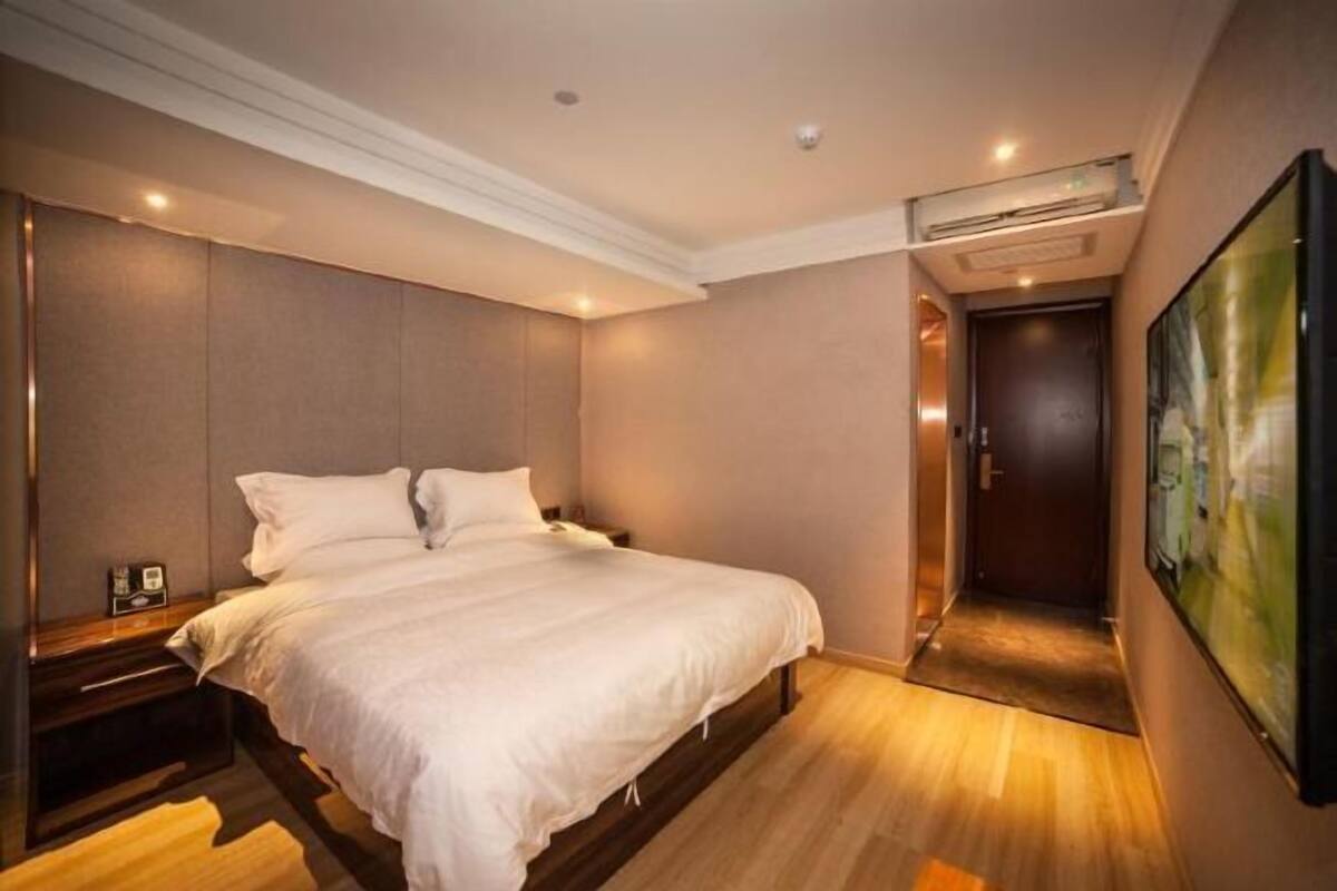 Habitación de hotel con una cama grande, una mesita de noche, un equipo de aire acondicionado y un cuadro en la pared.