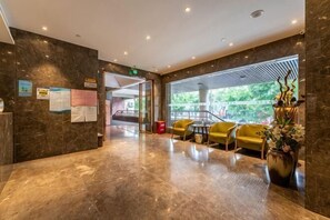 A lobby with a marble floor, yellow chairs, a reception desk, and a staircase leading to another area. - Baba Boutique Hotel (Xiamen)