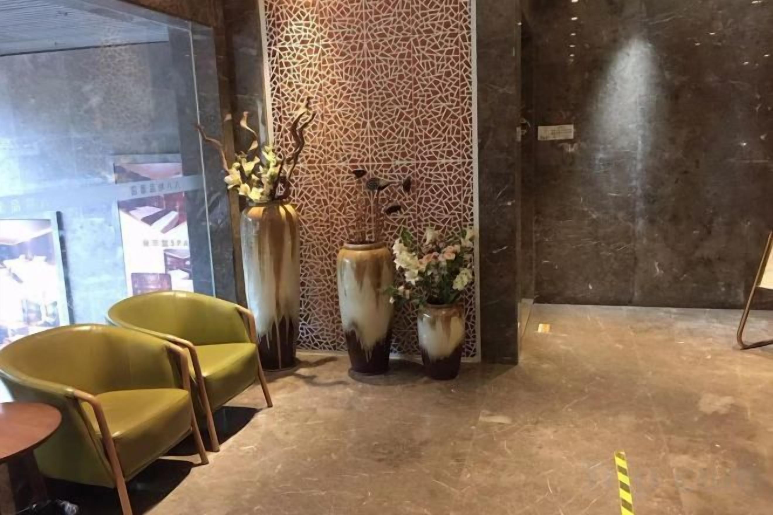 A lobby with a reception desk, two chairs, and decorative vases.