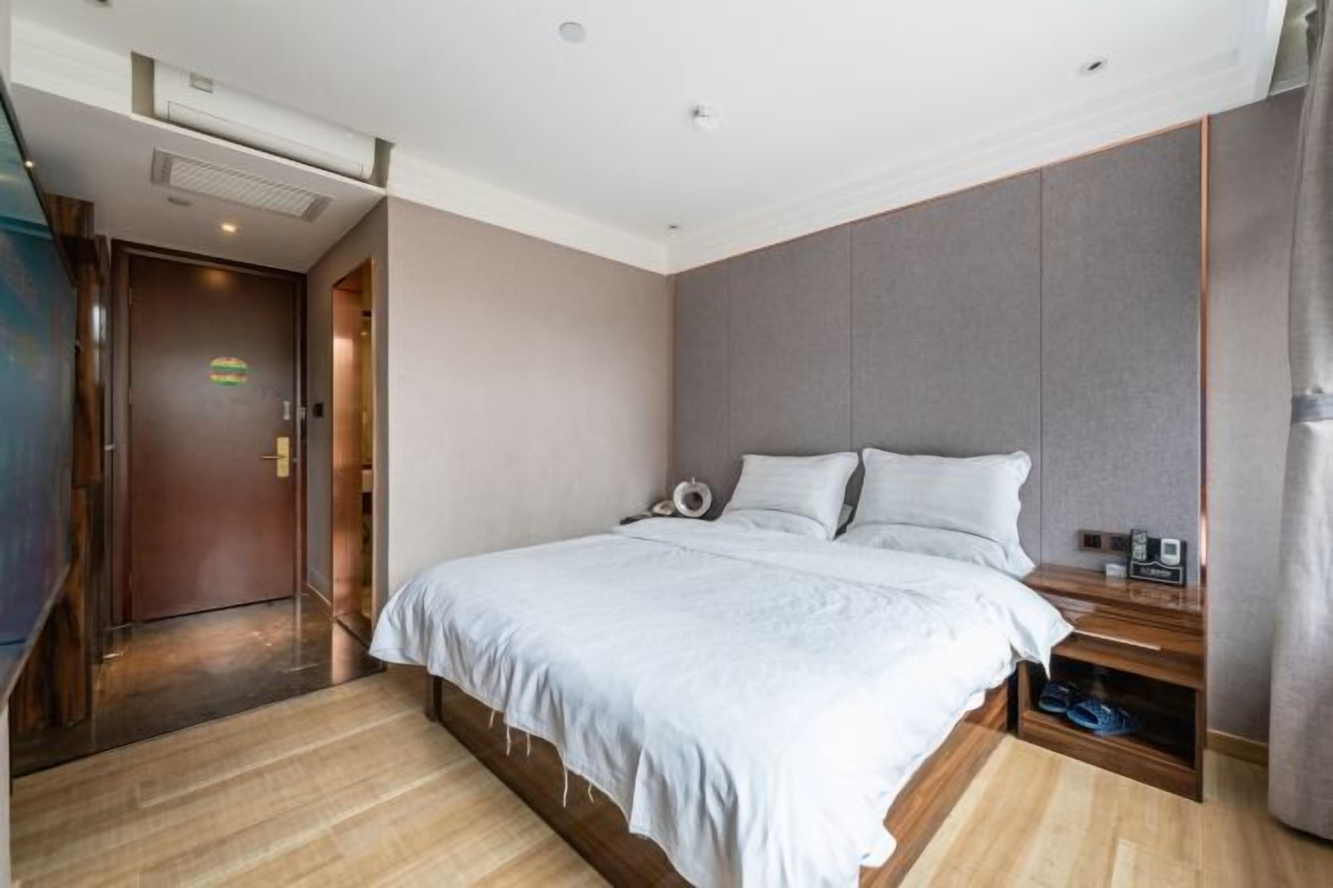 Una habitación de hotel moderna con una cama grande, una mesita de noche y un zapatero empotrado.