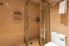 A bathroom with a glass shower enclosure, a toilet, and a shelf with toiletries. - Baba Boutique Hotel (Xiamen)