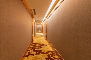 A hallway with patterned carpet, walls, and overhead lighting. - Baba Boutique Hotel (Xiamen)
