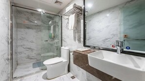 Ein Badezimmer mit Duschkabine, Toilette, Waschbecken und Spiegel.