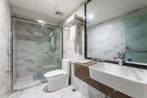 Une salle de bain avec une douche à parois de verre, des toilettes, un lavabo et un miroir.