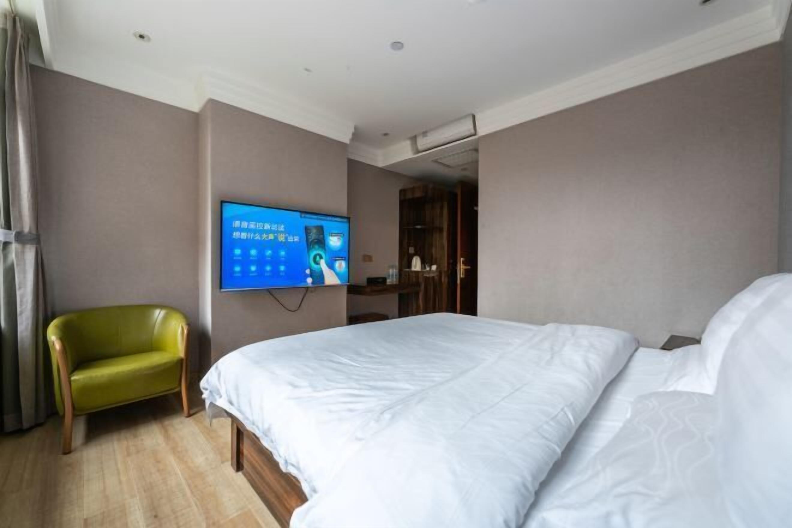 Una habitación de hotel con una cama, un televisor en la pared y una silla verde.