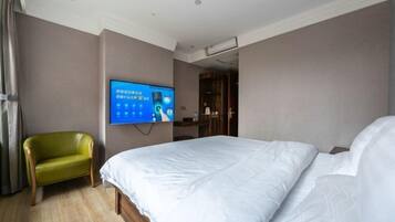 Una habitación de hotel con una cama, un televisor en la pared y una silla verde.