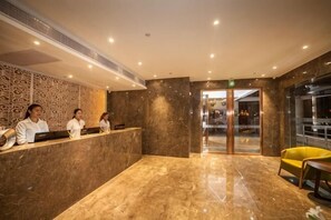 A hotel reception area with a marble floor, a reception desk, and a yellow armchair. - Baba Boutique Hotel (Xiamen)