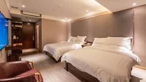 Ein Hotelzimmer mit zwei Betten, einem Fernseher, einem Schreibtisch und einem Sessel.