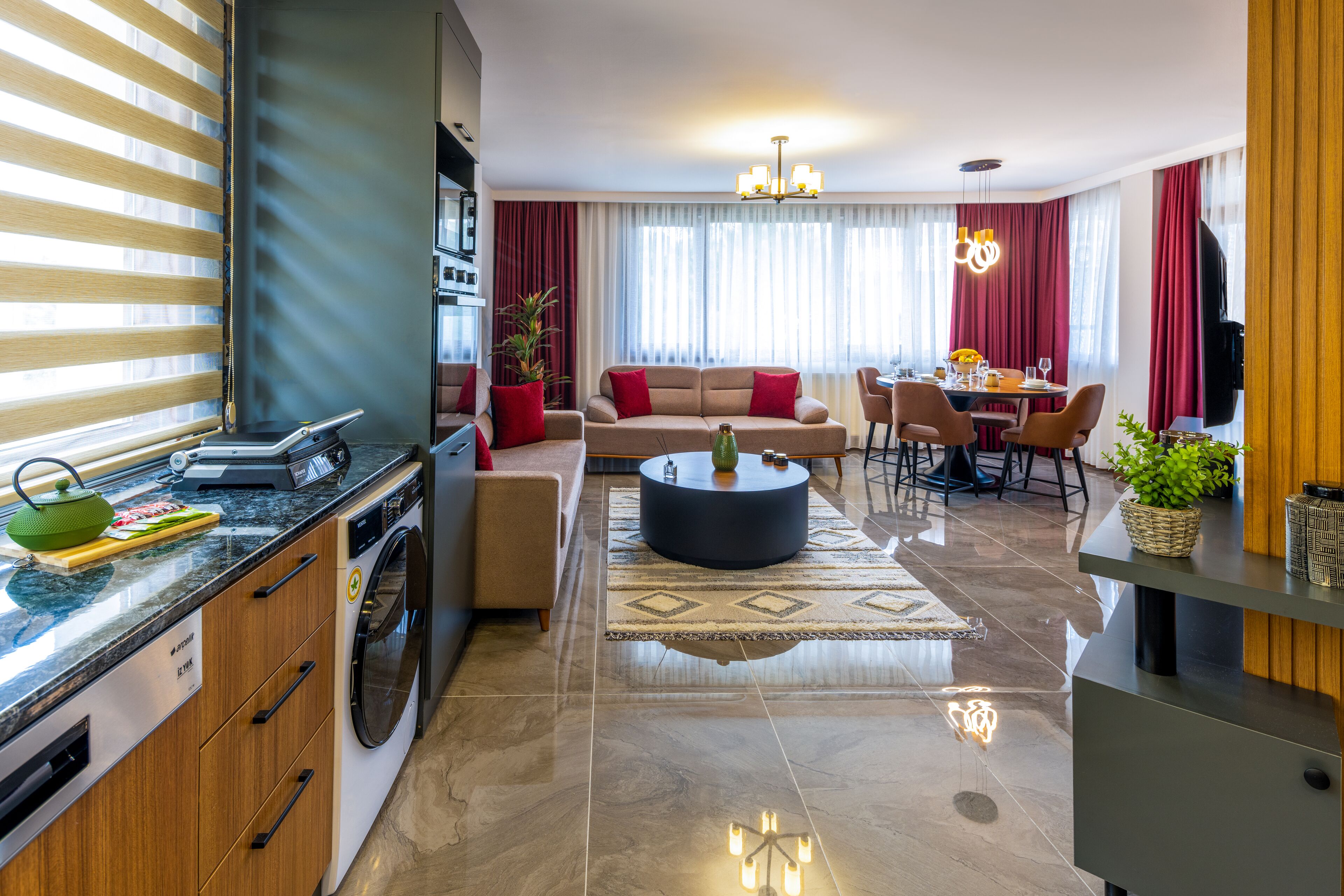 Ein modernes Wohnzimmer mit Sofa, Esstisch und Küchenzeile, einschließlich einer Waschmaschine.