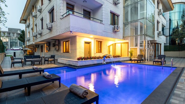 Un hotel modern amb piscina, zones d'estar a l'exterior i entrada ben il·luminada.