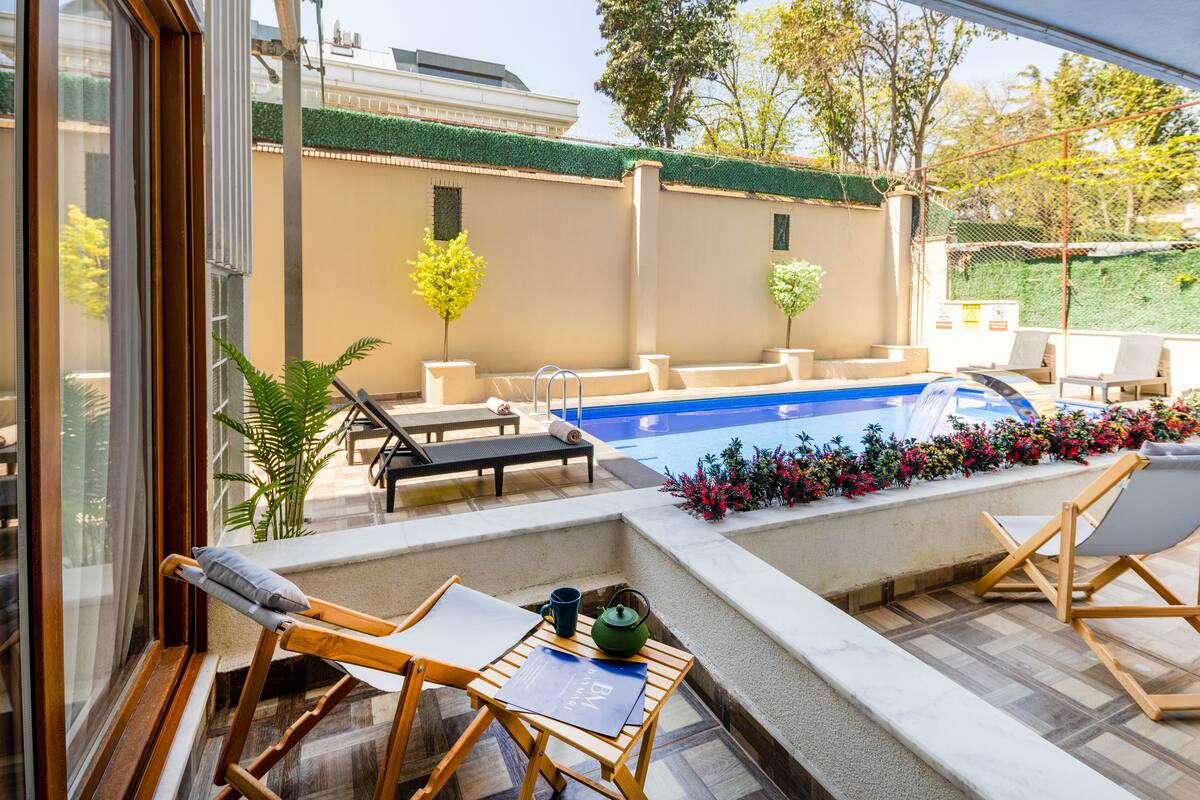 A poolside area with lounge chairs, a small table, and a pool.