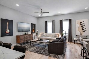 A modern living room with a sofa, coffee table, and a dining area with chairs.