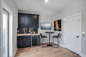 Een moderne keuken met donkere kastjes, een inbouwoven en een klein eethoekje met twee stoelen en een tafel.