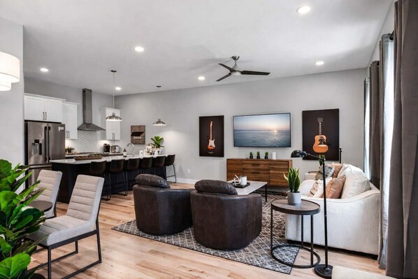 A modern living room with a sofa, armchairs, a coffee table, and a TV.
