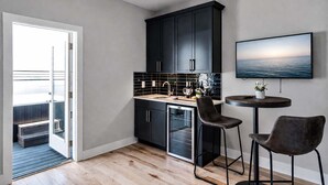 A modern kitchen with dark cabinets, a countertop, and a dining area with two chairs. - Skyline Hot Tub Retreat • Walk to Honky Tonks (Nashville)